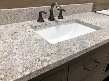 Remodeled bathroom vanity with granite counter and white sink.