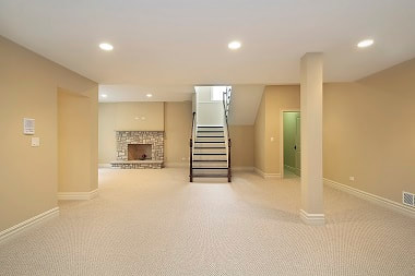 Picture of finished basement with bright lighting, fire place and stairway in Cheyenne Wyoming remodeled basement.